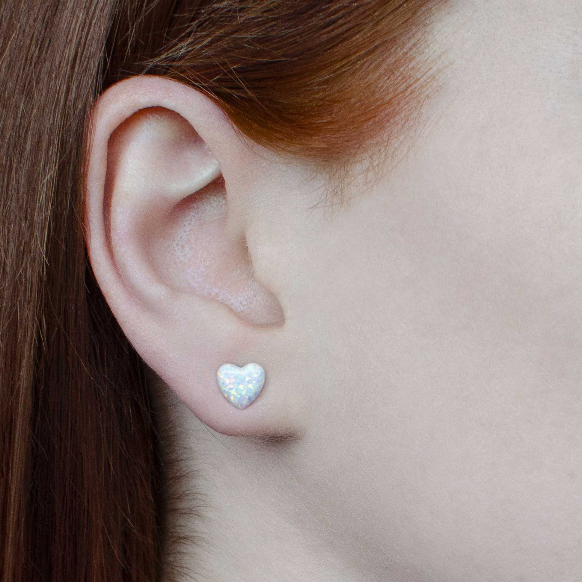 Woman wearing white Opal heart studs in earlobe
