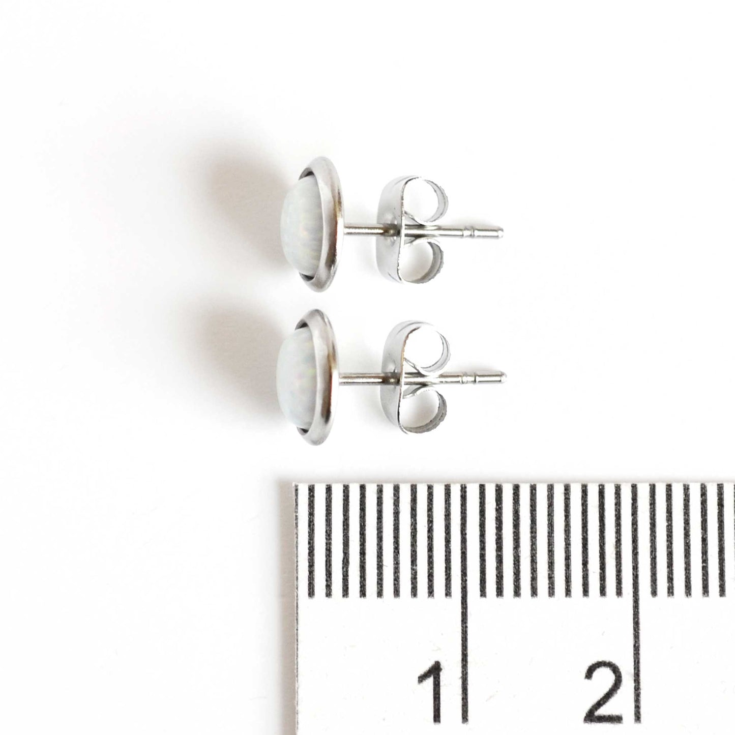 8mm wide white Opal stud earrings next to ruler